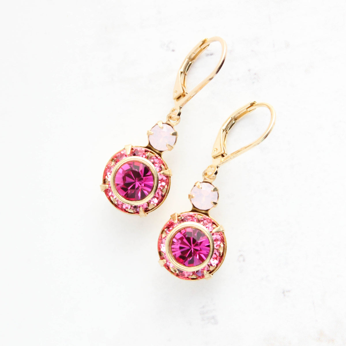 Gold earrings with pink gemstones on a white background