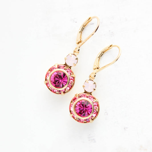 Gold earrings with pink gemstones on a white background