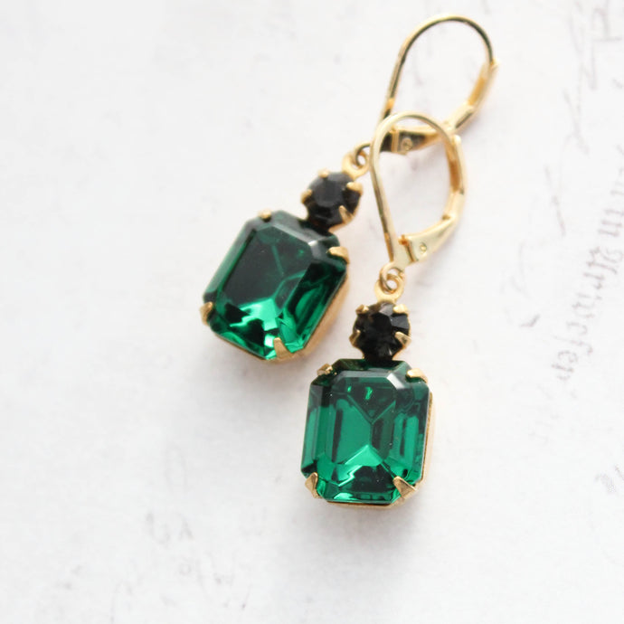 Green gemstone earrings with gold hooks on a white background
