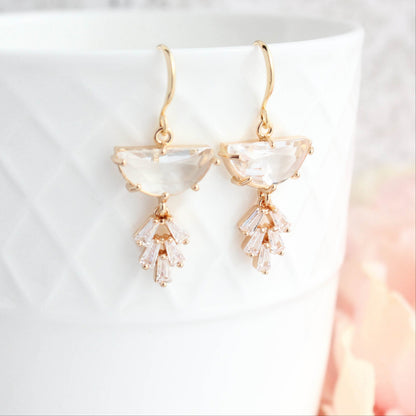 A pair of Art Deco style gold-plated dangle earrings with a half moon glass stone and a sparkling baguette multi-stone leaf design, displayed against a white background.