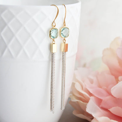 Long chain tassel earrings with aqua glass jewels and ivory gold chain, displayed hanging from a white cup.