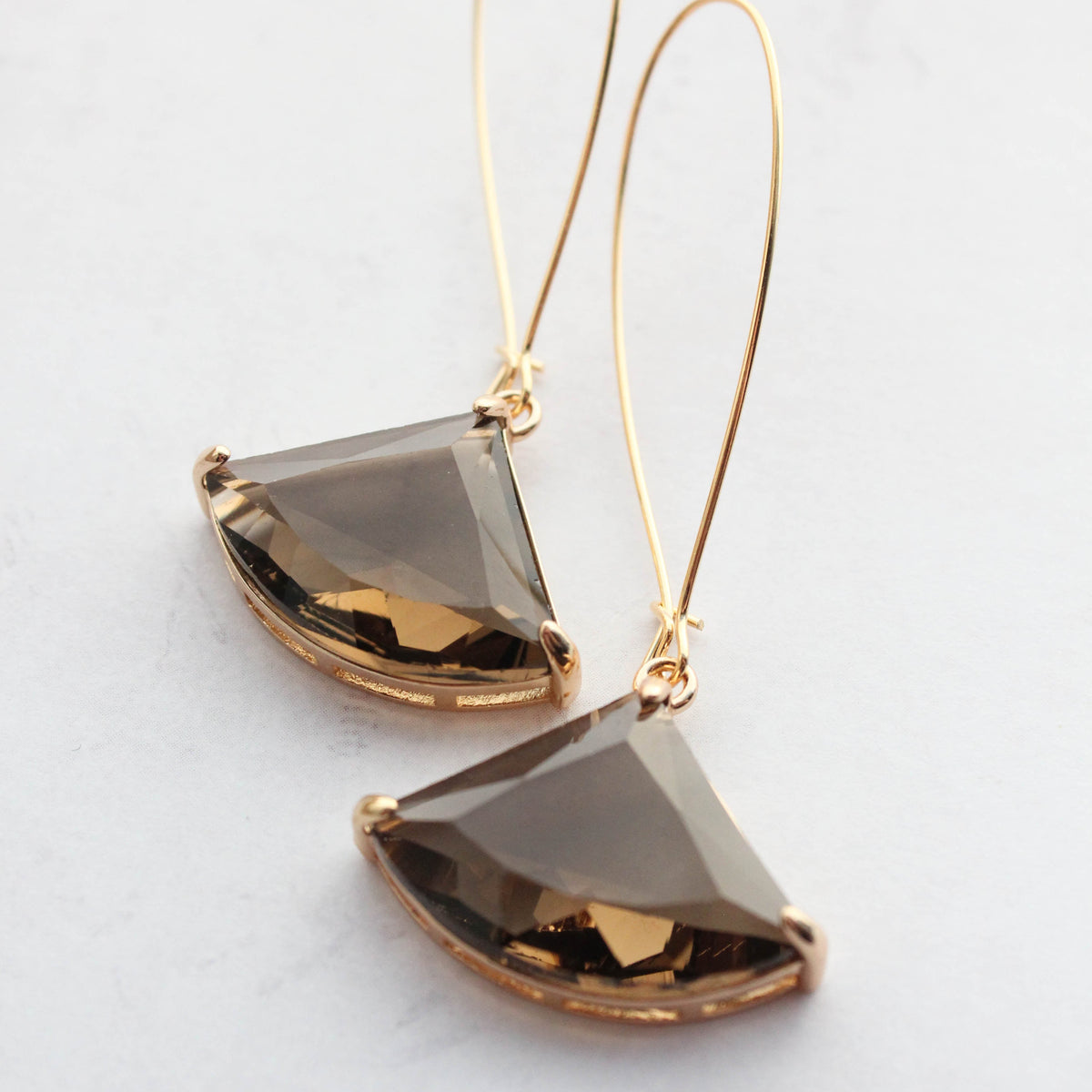 A pair of art deco fan glass dangle earrings in brown color with gold plating and gold wired hooks.