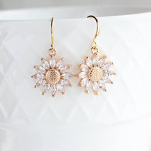 Load image into Gallery viewer, Gold sunflower-shaped earrings with clear gemstones on a white background