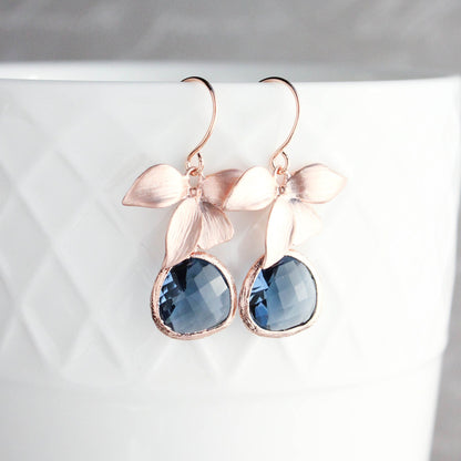 Rose gold orchid earrings with clear glass jewels in navy blue color, displayed on a white surface.
