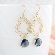 Load image into Gallery viewer, Gold-colored dangle earrings with navy blue glass jewels, designed as a laurel wreath with leafy vine hoops, displayed on a white surface.