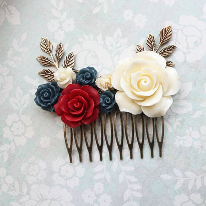 A bridal hair comb featuring a floral design with cream, red, and navy blue flowers on an antique brass leafy branch comb.